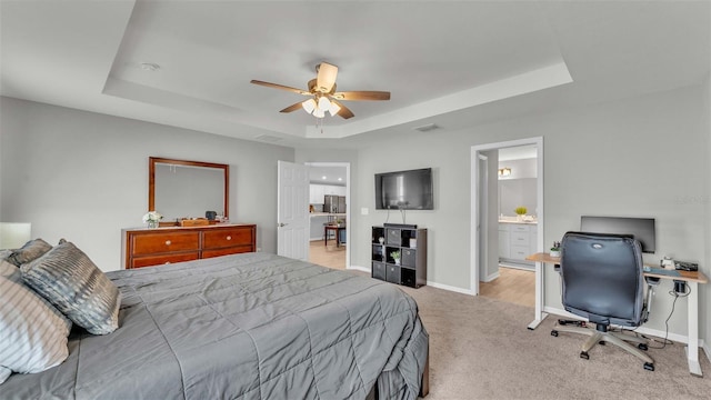 carpeted bedroom with ceiling fan, ensuite bathroom, and a tray ceiling