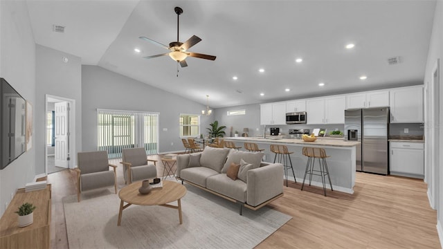 living room with a ceiling fan, light wood-style floors, visible vents, and high vaulted ceiling