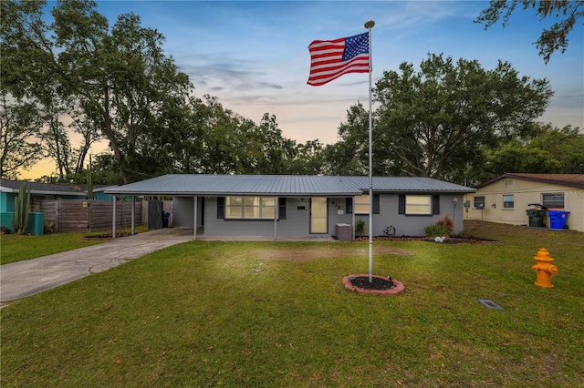 ranch-style home with central air condition unit, a carport, and a yard