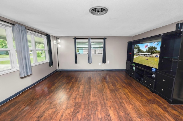 unfurnished living room with dark hardwood / wood-style flooring and a textured ceiling