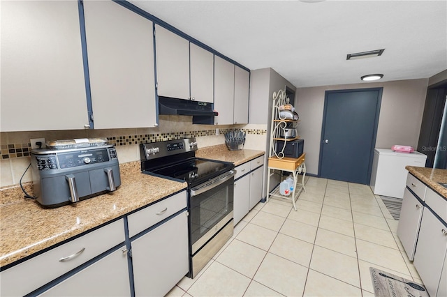 kitchen with light tile patterned floors, decorative backsplash, white cabinets, and electric range