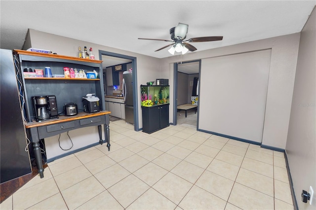 kitchen featuring ceiling fan, light tile patterned flooring, and stainless steel refrigerator