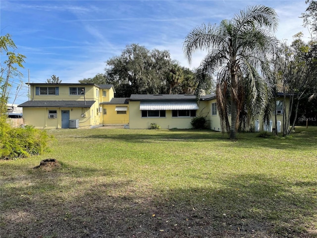 rear view of property with a lawn and central AC