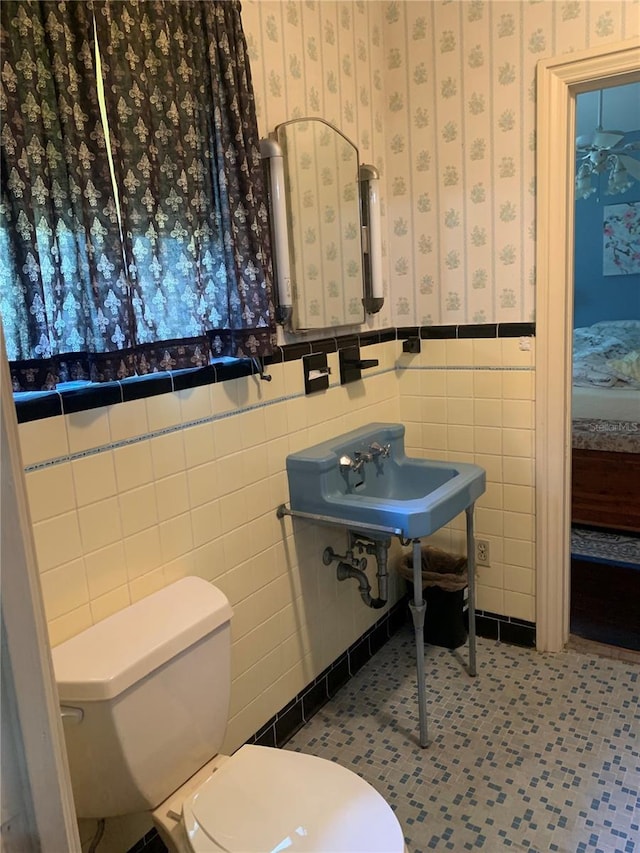 bathroom with tile walls, toilet, tile patterned floors, and sink