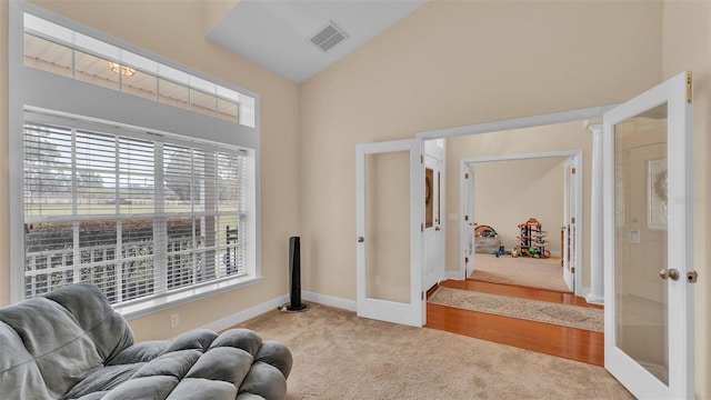 living area with high vaulted ceiling, light colored carpet, french doors, and ornate columns