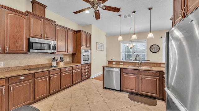 kitchen featuring sink, appliances with stainless steel finishes, tasteful backsplash, light stone counters, and decorative light fixtures