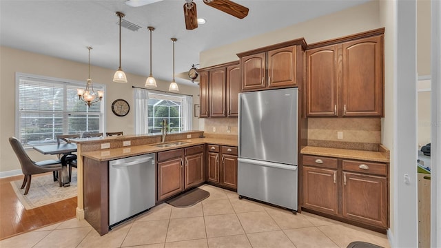 kitchen with light tile patterned flooring, appliances with stainless steel finishes, pendant lighting, sink, and backsplash