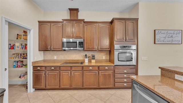 kitchen featuring backsplash, light tile patterned flooring, light stone countertops, and appliances with stainless steel finishes