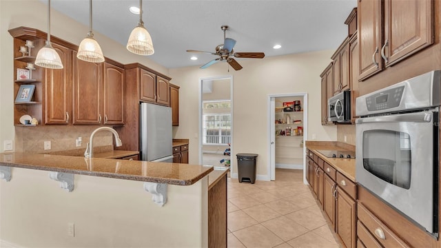 kitchen featuring a kitchen bar, decorative light fixtures, kitchen peninsula, and appliances with stainless steel finishes