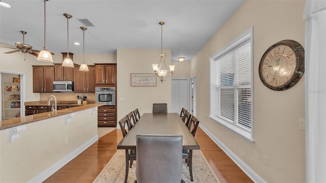 dining space featuring ceiling fan with notable chandelier and light hardwood / wood-style flooring