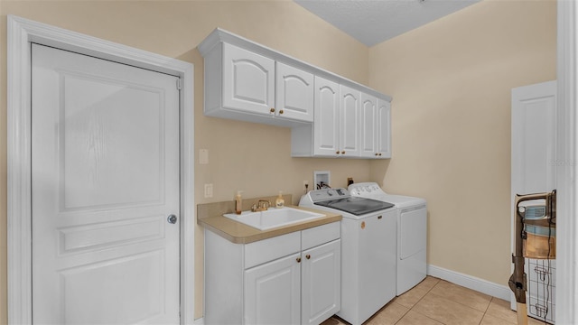 laundry area with sink, cabinets, a textured ceiling, light tile patterned flooring, and separate washer and dryer