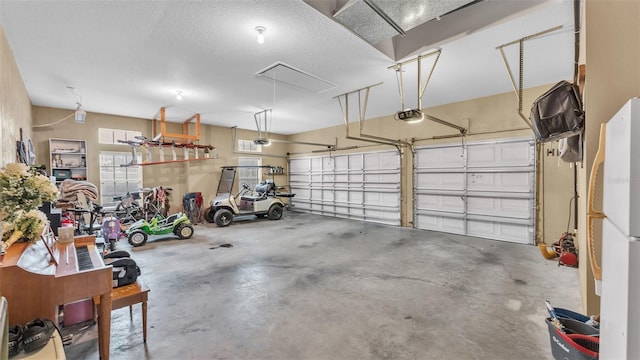 garage with a garage door opener and white fridge