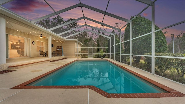 pool at dusk with a patio area and glass enclosure