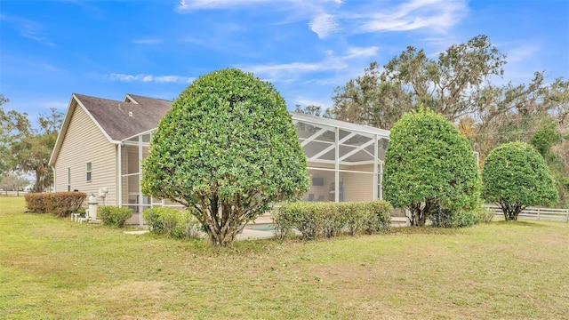 view of side of home featuring a lanai and a lawn