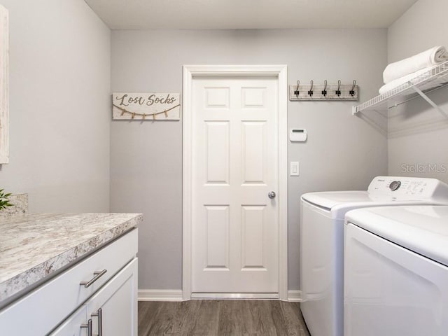 clothes washing area featuring cabinets, washer and clothes dryer, and dark wood-type flooring