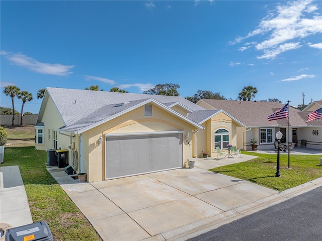 ranch-style home with driveway, central AC unit, an attached garage, a front yard, and stucco siding