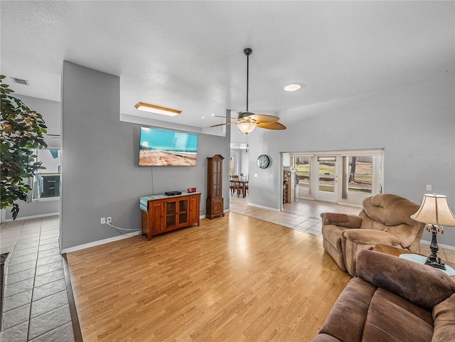 living area featuring visible vents, baseboards, a ceiling fan, a textured ceiling, and light wood-type flooring