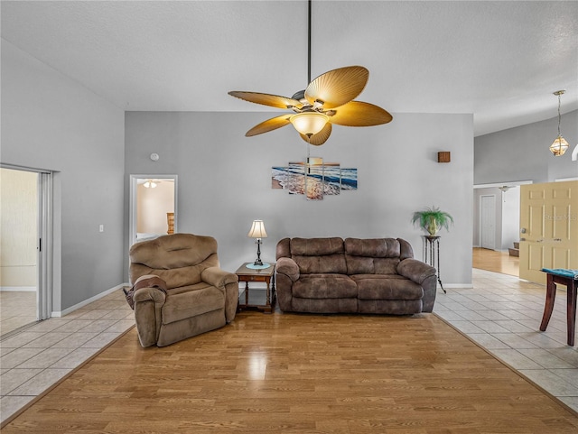 living room with a textured ceiling, high vaulted ceiling, light wood-style flooring, and a ceiling fan