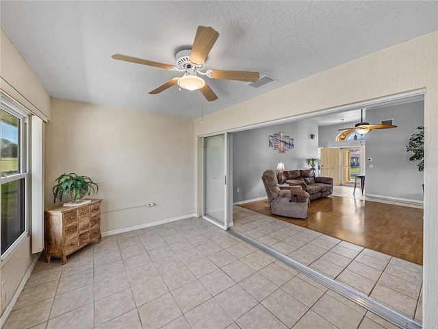 sitting room featuring a ceiling fan, visible vents, a textured ceiling, and light tile patterned floors