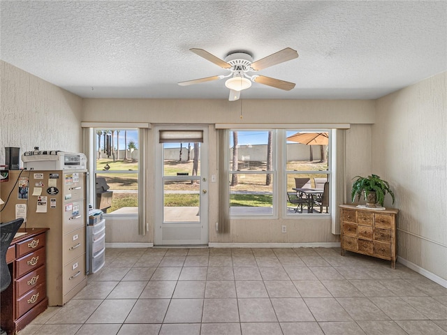 doorway to outside with a textured wall, light tile patterned flooring, and a ceiling fan