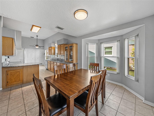 dining room featuring a textured ceiling, light tile patterned flooring, visible vents, and baseboards