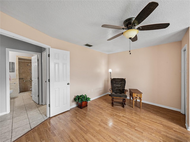 unfurnished room with visible vents, a textured ceiling, light wood-style flooring, and baseboards