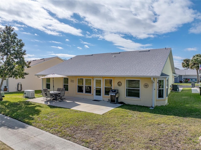 rear view of property featuring central AC unit, a shingled roof, a lawn, stucco siding, and a patio area