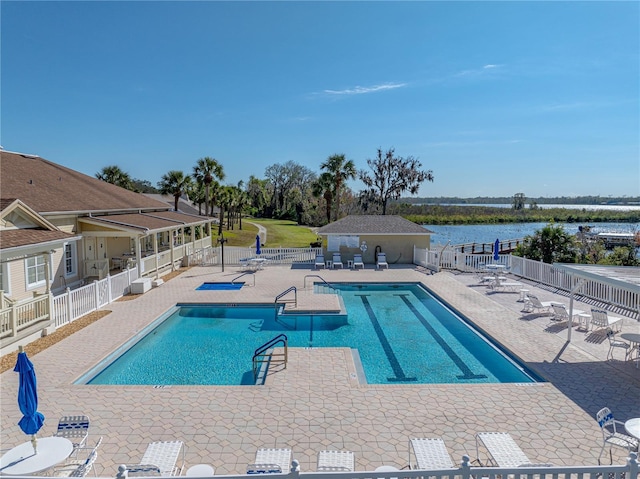 pool featuring a patio, a water view, and fence