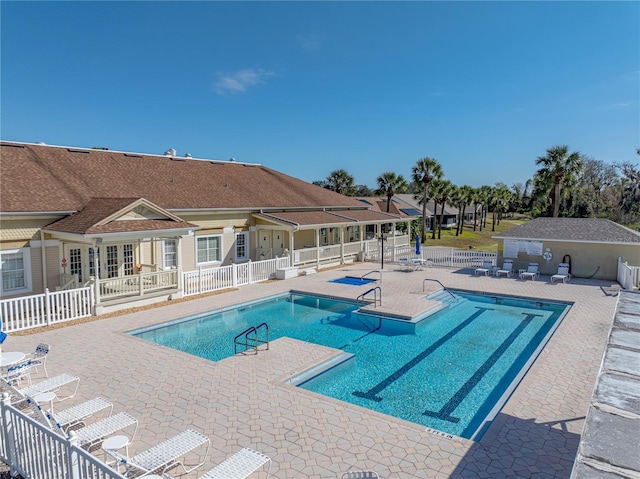 community pool with a patio area and fence