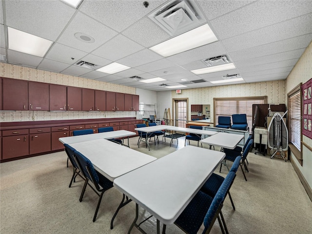 interior space with a paneled ceiling, wallpapered walls, and visible vents