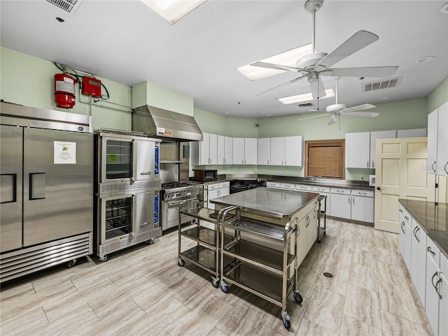 kitchen with premium appliances, visible vents, white cabinets, wall chimney exhaust hood, and dark countertops