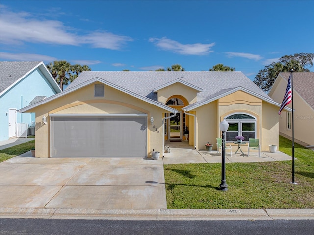 view of front of property featuring a garage, driveway, a front yard, and stucco siding