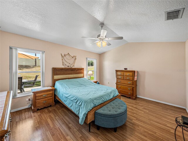 bedroom with visible vents, vaulted ceiling, baseboards, and wood finished floors