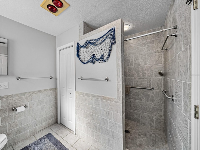 full bathroom featuring a textured ceiling, tiled shower, and tile walls