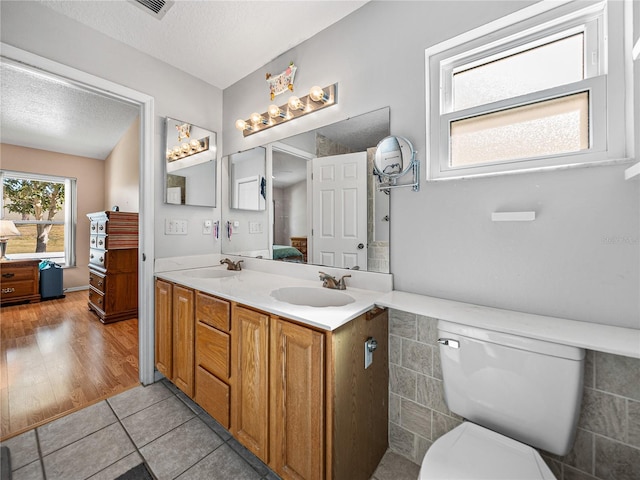 bathroom featuring a sink, a textured ceiling, ensuite bathroom, and double vanity