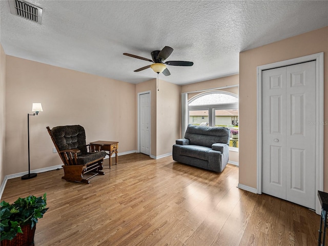 sitting room with visible vents, ceiling fan, baseboards, and wood finished floors