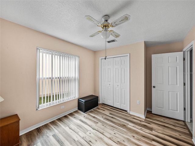 unfurnished bedroom with baseboards, a closet, visible vents, and wood finished floors