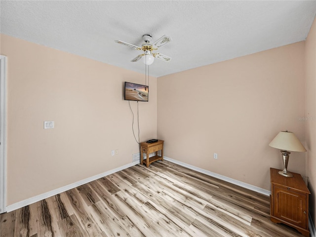 unfurnished room with ceiling fan, a textured ceiling, baseboards, and wood finished floors