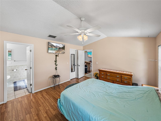 bedroom with visible vents, a ceiling fan, lofted ceiling, wood finished floors, and a textured ceiling