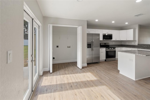 kitchen featuring light stone countertops, white cabinetry, stainless steel appliances, french doors, and light hardwood / wood-style floors