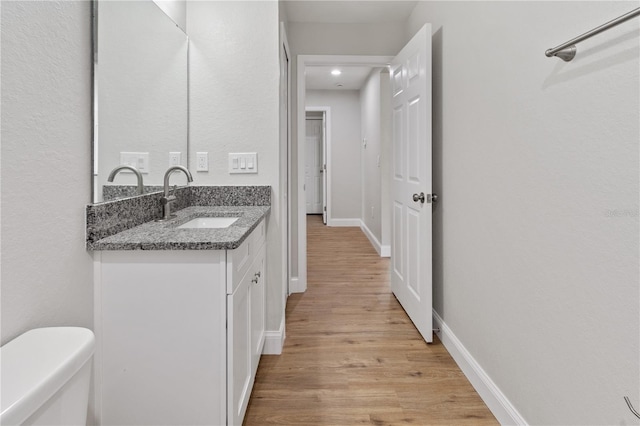 bathroom with vanity, toilet, and hardwood / wood-style flooring