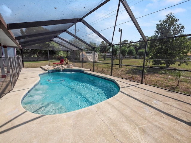 view of swimming pool with pool water feature, a yard, glass enclosure, and a patio