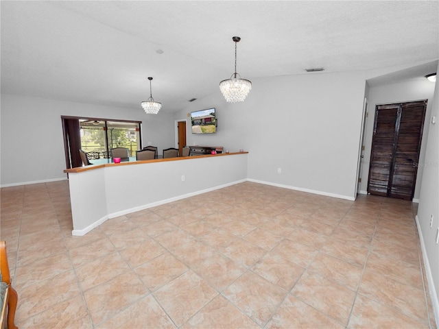 kitchen with a textured ceiling, decorative light fixtures, light tile patterned flooring, and kitchen peninsula