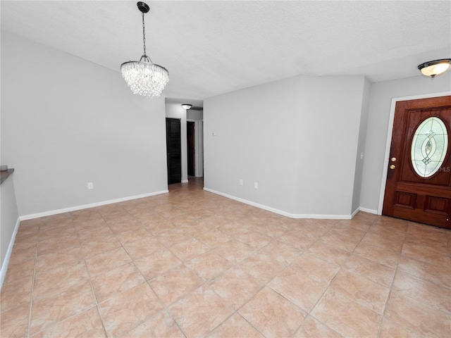 tiled foyer entrance featuring a textured ceiling and a notable chandelier