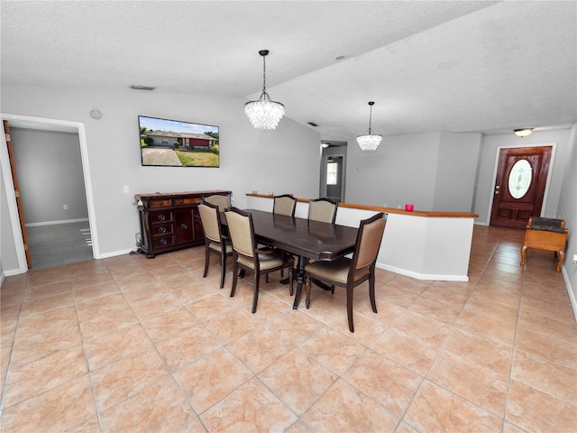 dining room featuring a textured ceiling, a healthy amount of sunlight, light tile patterned floors, lofted ceiling, and an inviting chandelier