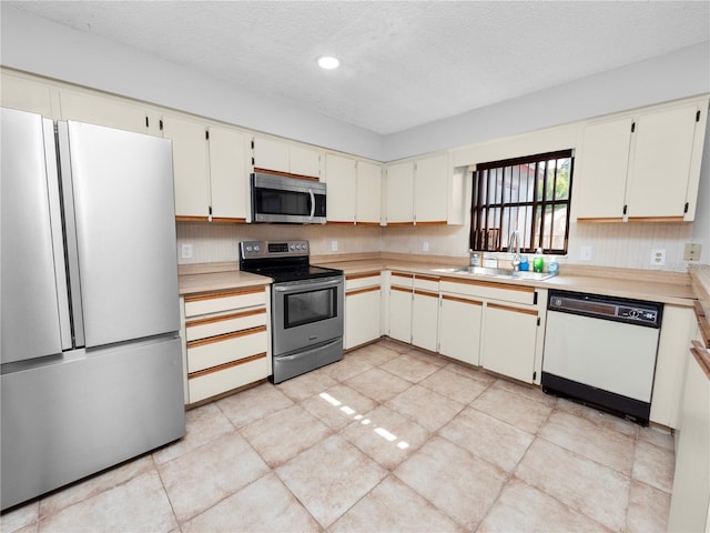 kitchen featuring appliances with stainless steel finishes, white cabinetry, a textured ceiling, and sink