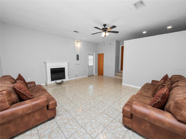 living room with light tile patterned flooring, a textured ceiling, and ceiling fan