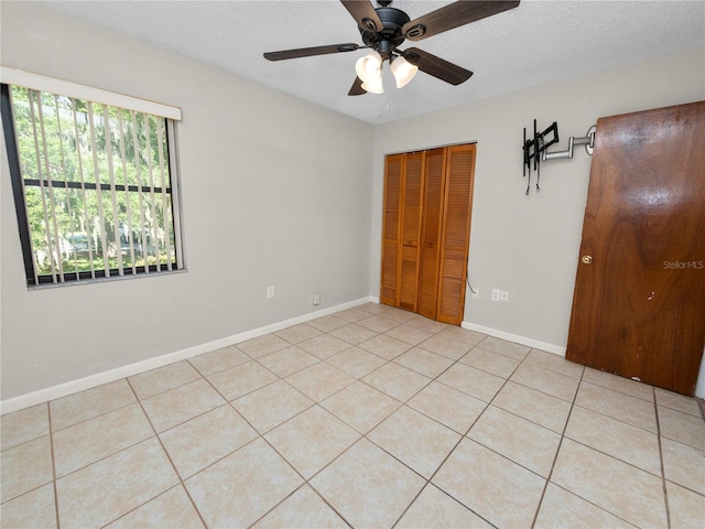 tiled spare room with a textured ceiling and ceiling fan