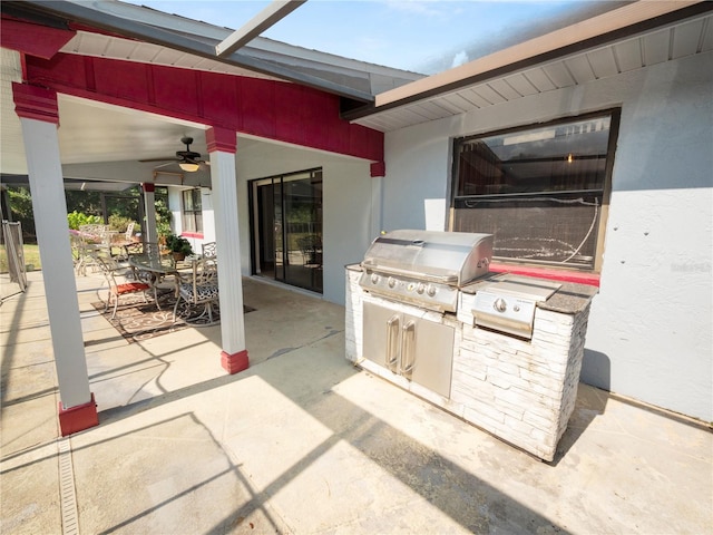 view of patio featuring ceiling fan, a grill, glass enclosure, and exterior kitchen