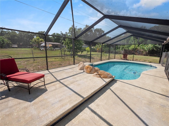 view of pool with a patio, glass enclosure, and a yard